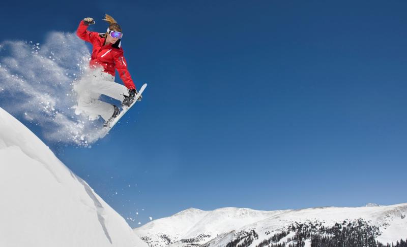 Jente kjører snowboard på fjelltopp