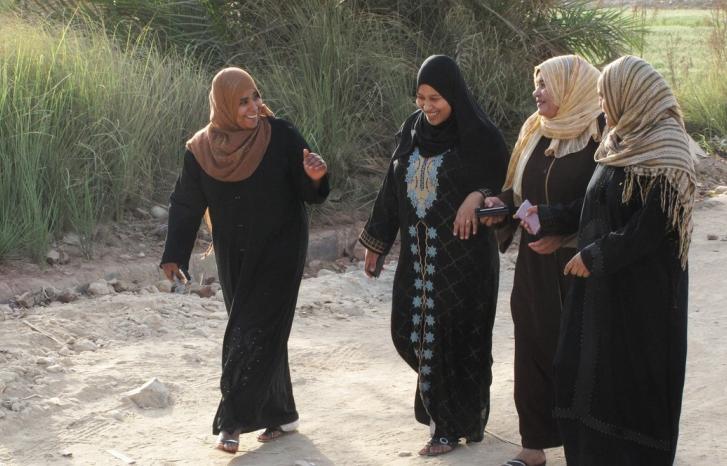 Fire egyptiske kvinner går langs en landevei og prater
