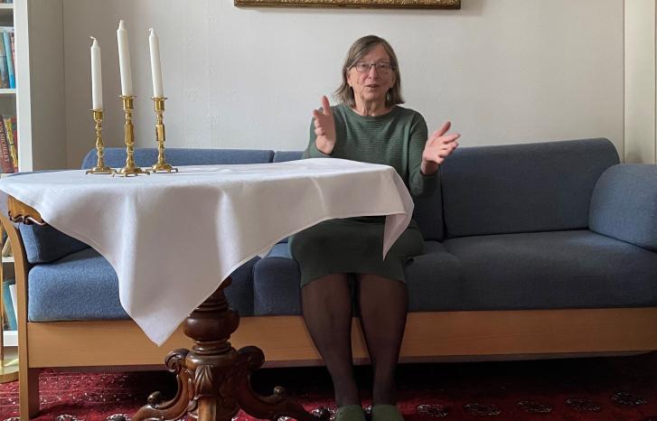 Charlotte Koren sittende i blå sofa ved et bord med hvit duk