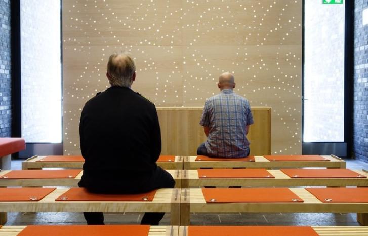 To menn sitter med ryggen til foran et vindu i Halden fengsel