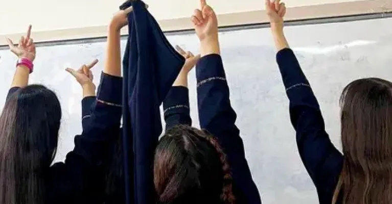 Tre jenter har tatt av seg sløret og viser fingeren til et bilde av iranske autoritetsfigurer