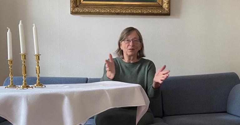 Charlotte Koren sittende i blå sofa ved et bord med hvit duk
