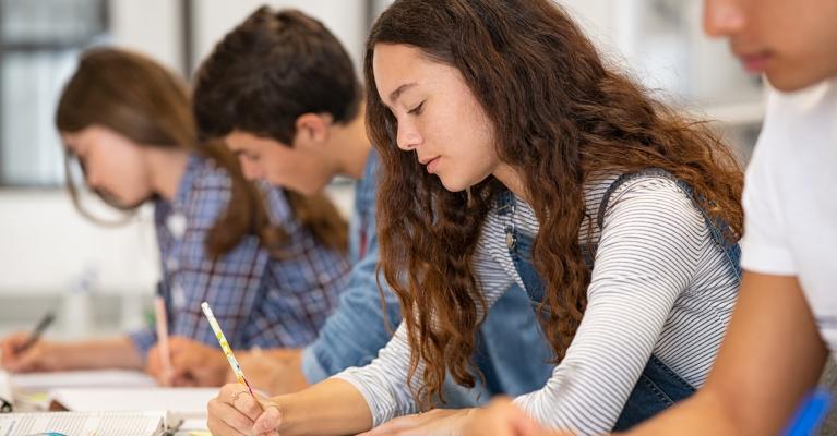 Fire ungdommer sitter i et klasserom og skriver