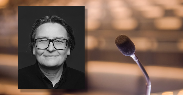 Portrettfoto av Ragnhild Hennum, dekan ved UiO, mot bakgrunn med mikrofon og tomme stolrader