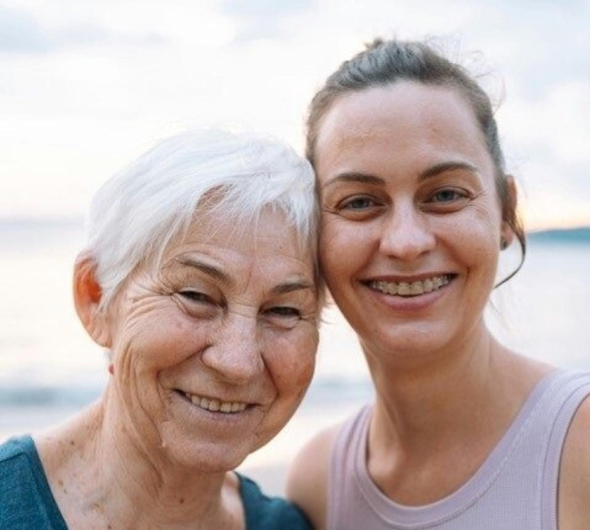 Up close, faces of two women close together, smiling, one young and one old