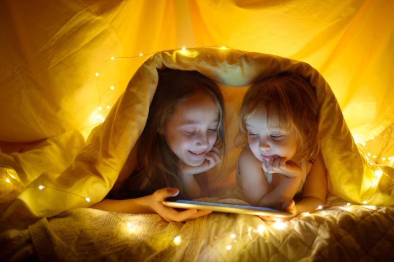 To småjenter leser nettbrett i telt