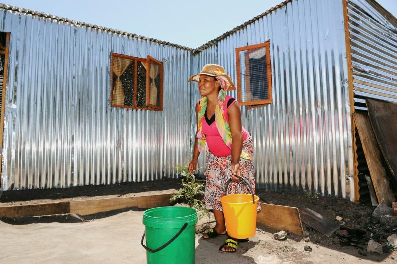 Kvinne henter vann til hjemmet sitt i Klipheuwel i Sør-Afrika 