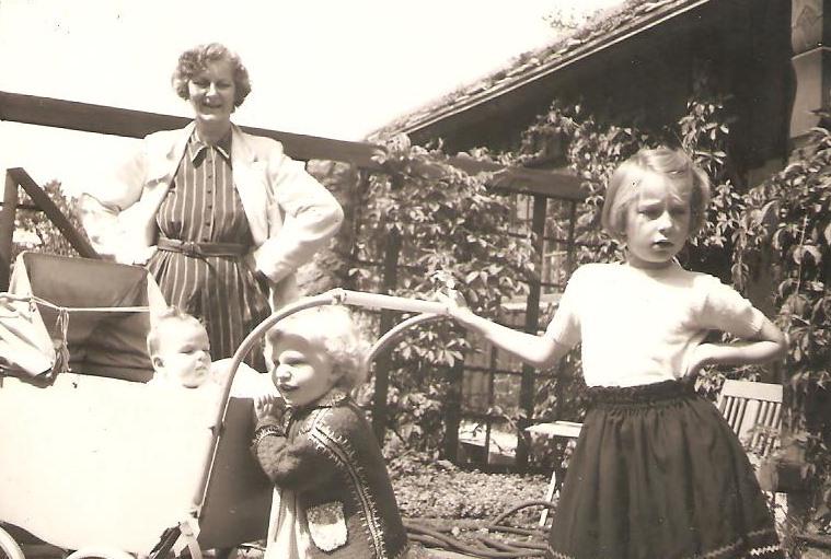 Sort-hvitt foto fra 1953 av Charlotte Koren som barn med sine to yngre søstre og moren foran mormorens hus på Lillevann.