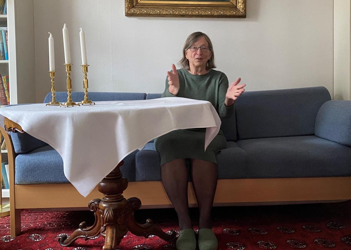 Charlotte Koren sittende i blå sofa ved et bord med hvit duk