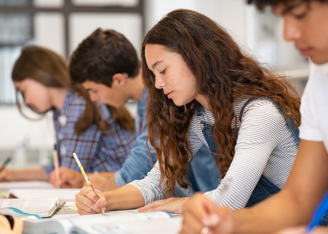 Fire ungdommer sitter i et klasserom og skriver