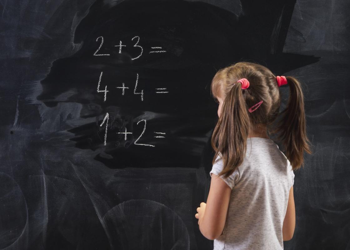 Skolejente med musefletter skriver tall på en tavle