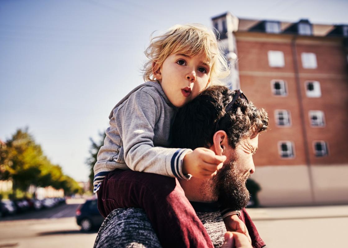 Gutt sitter på skuldrene til mann