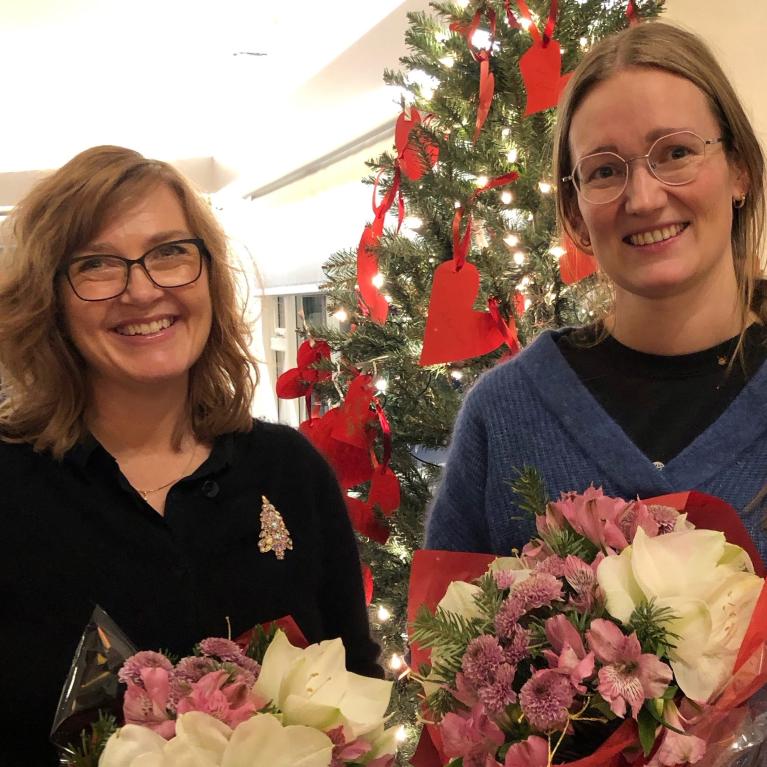 To kvinner med blomsterbuketter foran juletre To kvinner med blomsterbuketter foran juletre
