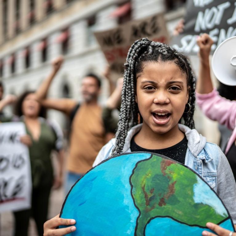Jente holder bilde av jordkloden i klimademonstrasjon