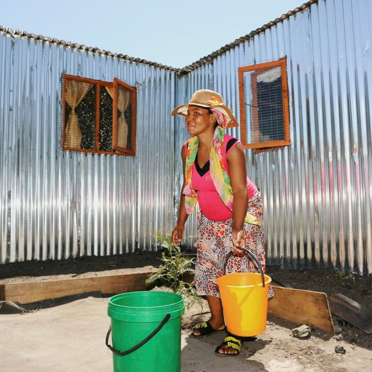 Kvinne henter vann til hjemmet sitt i Klipheuwel i Sør-Afrika 