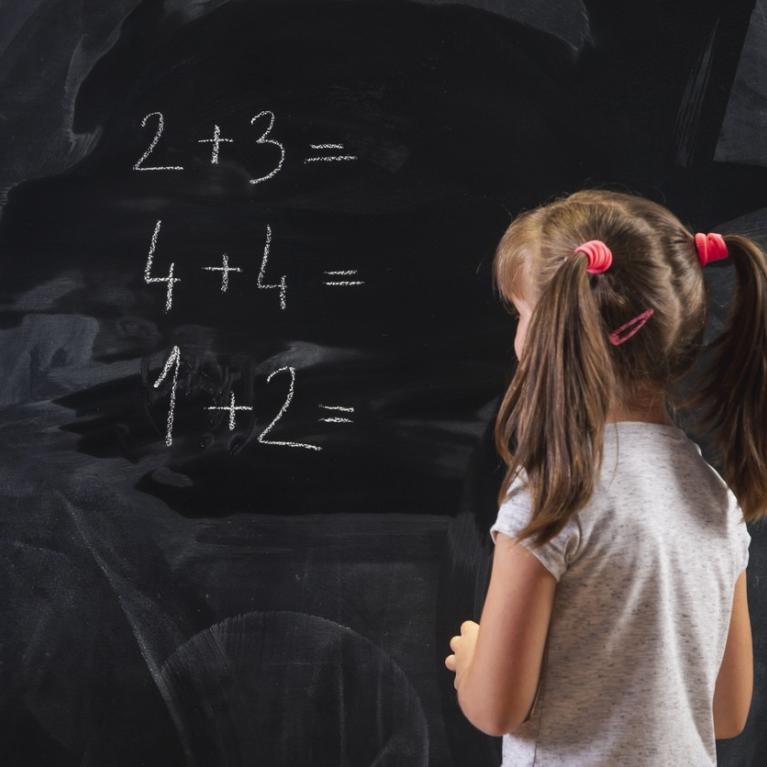 Skolejente med musefletter skriver tall på en tavle